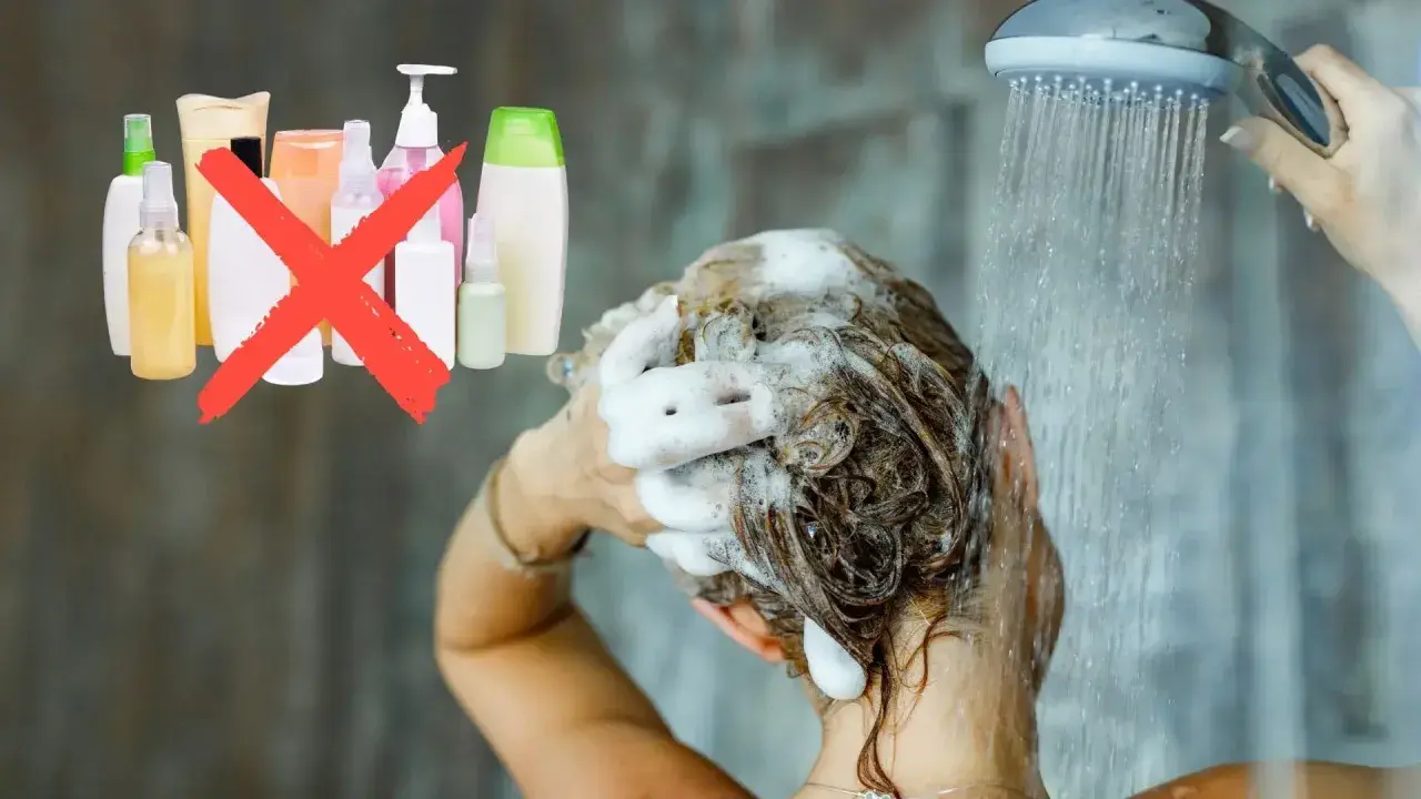 Frau wäscht sich die Haare unter der Dusche, Schaum im Haar. Eine rote durchgestrichene Gruppe von Shampoo-Flaschen deutet auf haare waschen ohne shampoo hin.