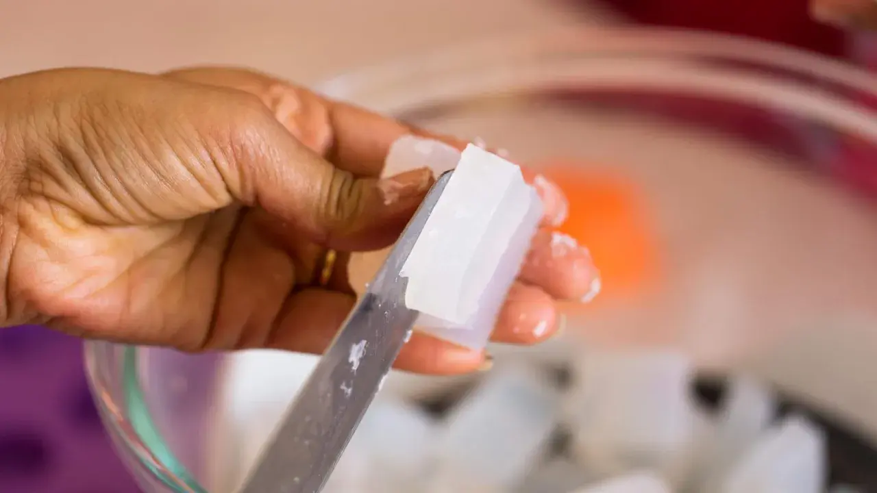 Hand schneidet klare Glycerinseife. Die Seife ist rein und wird bald auf der Haut angewendet.