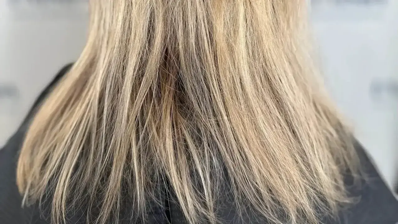 Nahaufnahme von schlecht blondierten Haaren mit deutlichen Strähnen und ungleichmäßiger Farbe.