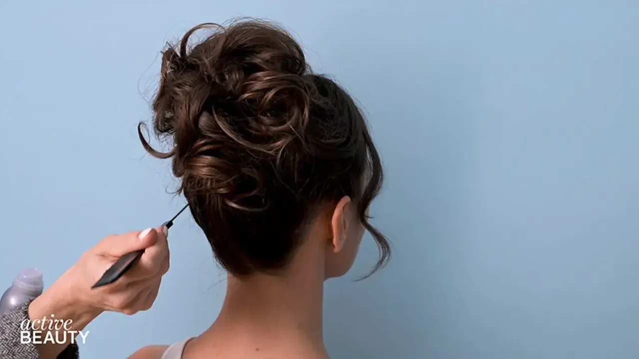 Eine Hand formt mit einem Kamm einen voluminösen, messy bun.