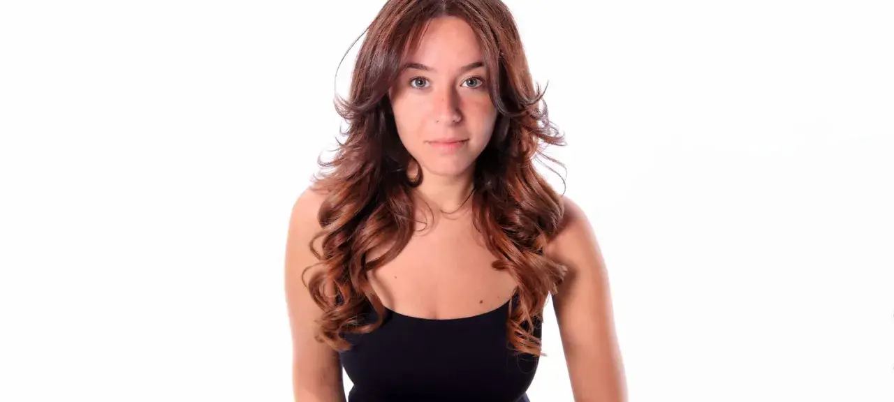 Frau mit langen, welligen Haaren, die einen Butterfly Cut trägt.
