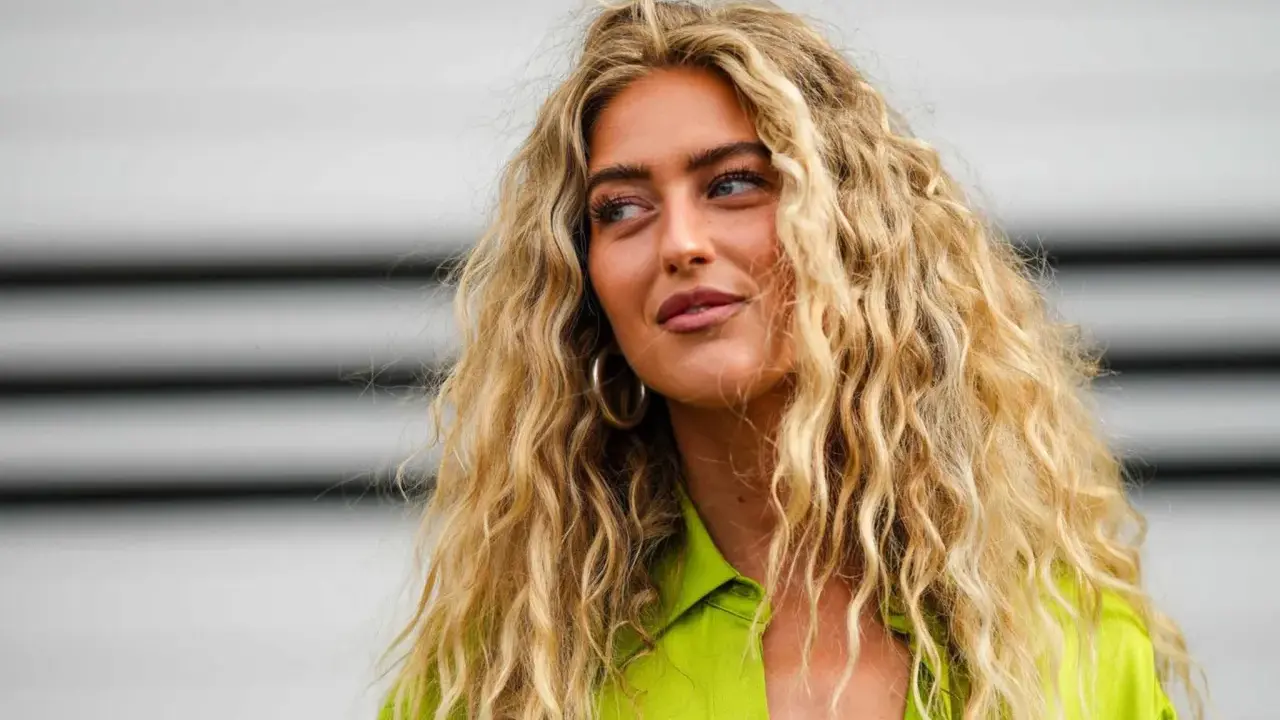 Frauen mit voluminösen, welligen Haaren, die durch locken ohne hitze erzielt wurden. Sie trägt ein leuchtend grünes Hemd.
