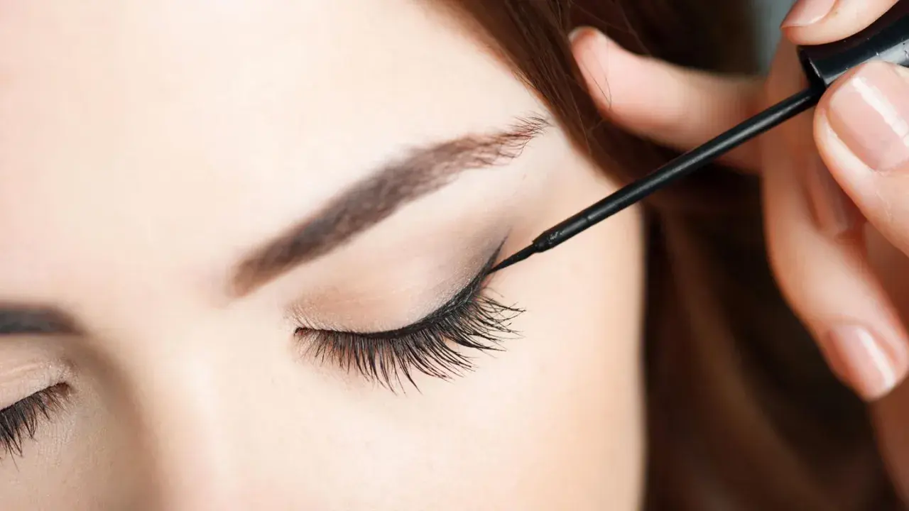 Eine Hand zieht mit schwarzem Eyeliner einen Wing für verführerische Cat Eyes.