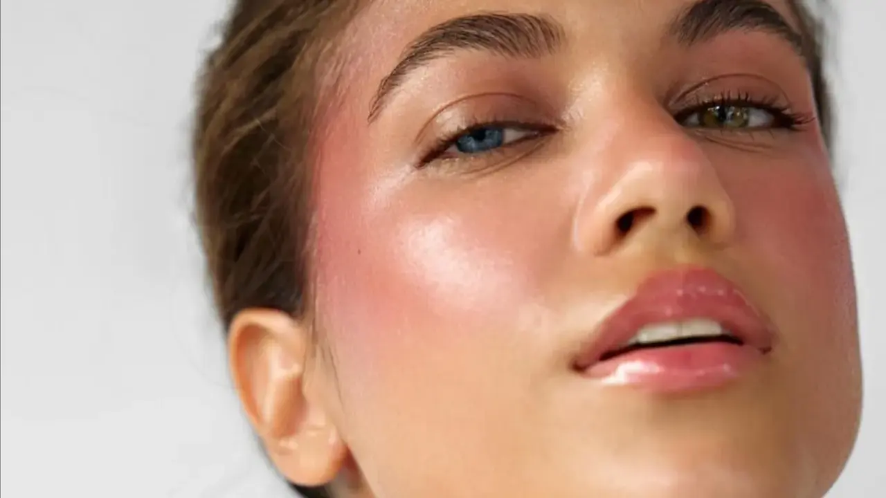 Ein **Hochzeitsgast** mit auffälligem Make-up: strahlende Haut, rosiger Blush und glänzende Lippen. Ihre Augen haben unterschiedliche Farben.