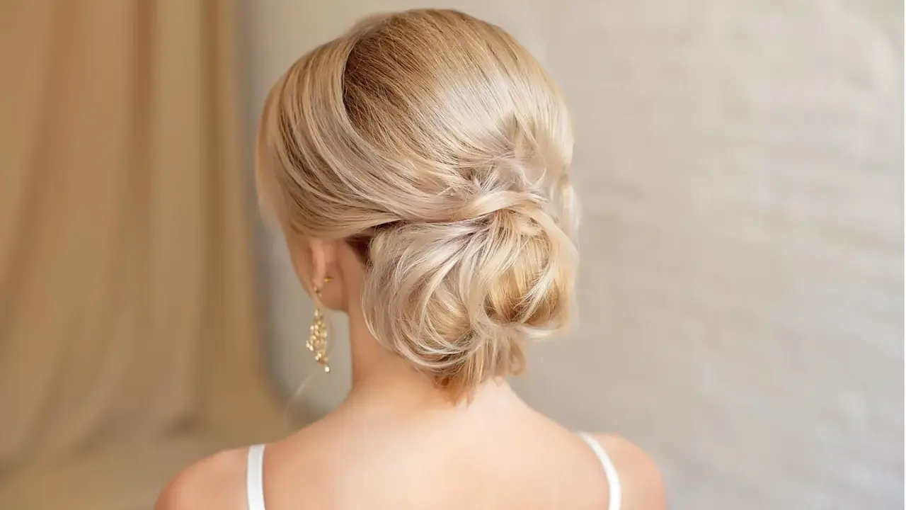 Elegante chignon frisur mit blondem Haar, kunstvoll zu einem tiefen Knoten gedreht.