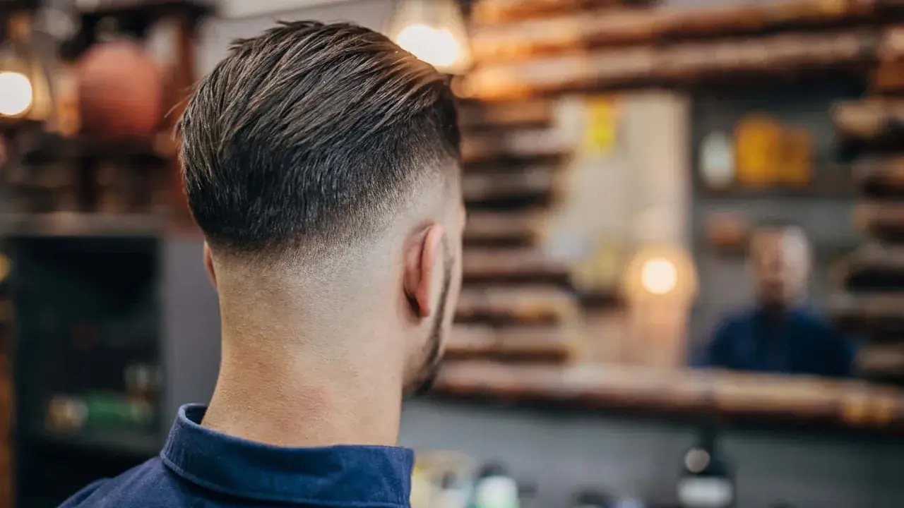 Mann mit einem modernen Haarschnitt, der einen **high taper** aufweist. Die Seiten sind kurz geschoren und gehen nahtlos in das längere Deckhaar über.