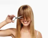 Frau mit Schere im blonden Haar, bereit, sich die Haare selber zu schneiden.