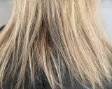 Nahaufnahme von schlecht blondierten Haaren mit deutlichen Strähnen und ungleichmäßiger Farbe.