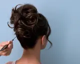 Eine Hand formt mit einem Kamm einen voluminösen, messy bun.