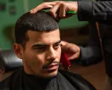 Ein Mann bekommt einen **langer buzz cut** beim Friseur. Die Haare werden mit einer Schere und einem Trimmer in Form gebracht.