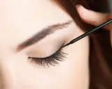 Eine Hand zieht mit schwarzem Eyeliner einen Wing für verführerische Cat Eyes.
