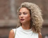 Frau mit voluminöser Dauerwelle, die auf die richtige Dauerwelle Pflege achtet.
