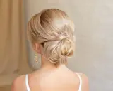 Elegante chignon frisur mit blondem Haar, kunstvoll zu einem tiefen Knoten gedreht.