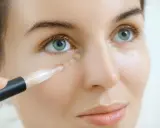 Frauenhand trägt Concealer auf, um Falten zu kaschieren. So gelingt das Concealer richtig auftragen bei Falten.