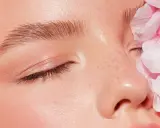 Sanftes Tages Make-up mit rosafarbenen Blütenblättern, die das Gesicht einer Frau zieren.