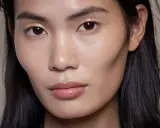 Ein Gesicht mit makellosem Teint und glänzenden Lippen. Das Make-up ist dezent, aber wirkungsvoll.