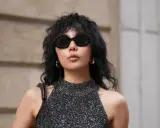 Frau mit schulterlangem Wolf Cut, Sonnenbrille und glitzerndem Top.
