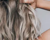 Hände im blonden, drahtigen Haar, das in Wellen fällt.