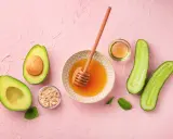 Zutaten für eine Gesichtsmaske selber machen: Avocado, Honig, Haferflocken, Gurke und Öl.