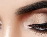 Nahaufnahme eines geschminkten Auges. Ein schimmernder Lidschatten wurde aufgetragen, mit einem dramatischen dunklen Smokey-Eye-Effekt.