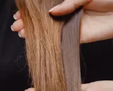 Hände halten zwei Strähnen Haar. Eine ist hellbraun und wirkt etwas struppig, die andere ist dunkler und glänzt. So bekomme ich glanz in meine haare.