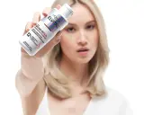 Frau hält L'Oréal Elvital Bond Repair Pre-Shampoo. Ideal für die Haarpflege bei trockenem Haar, repariert es geschädigte Haarbrücken.