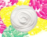 Cremige Textur einer leinsamen maske gesicht, umgeben von bunten Leinsamen in Pink, Gelb und Grün.