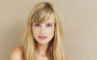 Blonde Frau mit blauen Augen und einem lässigen Pony, der aussieht, als hätte sie ihn selber geschnitten.
