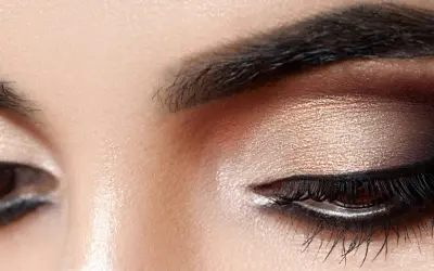 Nahaufnahme eines geschminkten Auges. Ein schimmernder Lidschatten wurde aufgetragen, mit einem dramatischen dunklen Smokey-Eye-Effekt.