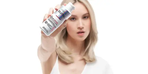 Frau hält L'Oréal Elvital Bond Repair Pre-Shampoo. Ideal für die Haarpflege bei trockenem Haar, repariert es geschädigte Haarbrücken.