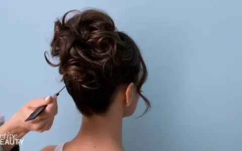Eine Hand formt mit einem Kamm einen voluminösen, messy bun.