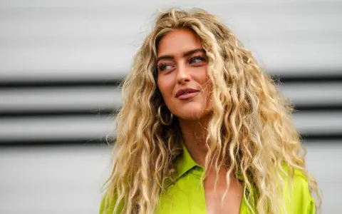 Frauen mit voluminösen, welligen Haaren, die durch locken ohne hitze erzielt wurden. Sie trägt ein leuchtend grünes Hemd.
