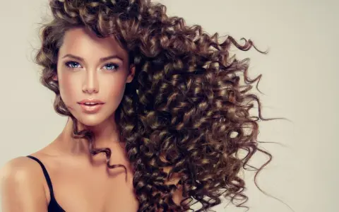 Frauenkopf mit vollem, braunem Lockenkopf, der die Curly Girl Methode zeigt.