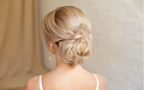 Elegante chignon frisur mit blondem Haar, kunstvoll zu einem tiefen Knoten gedreht.