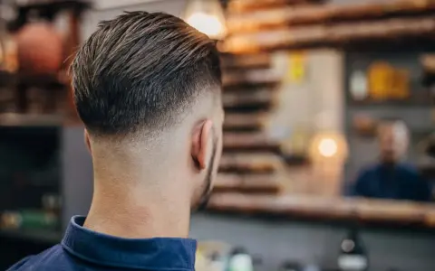 Mann mit einem modernen Haarschnitt, der einen **high taper** aufweist. Die Seiten sind kurz geschoren und gehen nahtlos in das längere Deckhaar über.