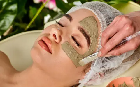Eine Frau erhält eine Gesichtsmaske. Die heilerde-wirkung haut wird durch das Auftragen der Maske mit einem Pinsel gezeigt.