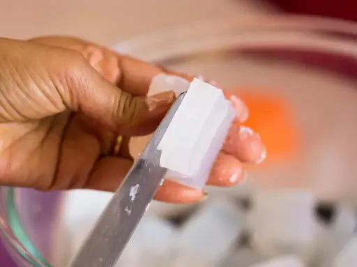 Hand schneidet klare Glycerinseife. Die Seife ist rein und wird bald auf der Haut angewendet.