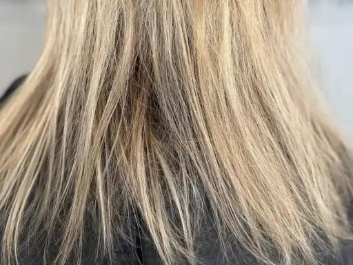 Nahaufnahme von schlecht blondierten Haaren mit deutlichen Strähnen und ungleichmäßiger Farbe.