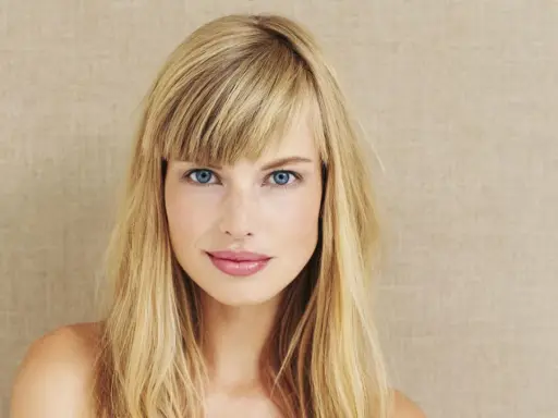 Blonde Frau mit blauen Augen und einem lässigen Pony, der aussieht, als hätte sie ihn selber geschnitten.