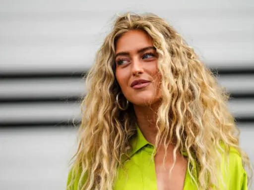 Frauen mit voluminösen, welligen Haaren, die durch locken ohne hitze erzielt wurden. Sie trägt ein leuchtend grünes Hemd.