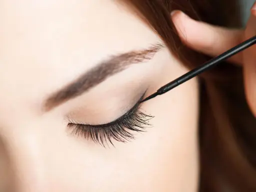 Eine Hand zieht mit schwarzem Eyeliner einen Wing für verführerische Cat Eyes.
