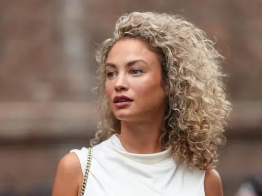 Frau mit voluminöser Dauerwelle, die auf die richtige Dauerwelle Pflege achtet.