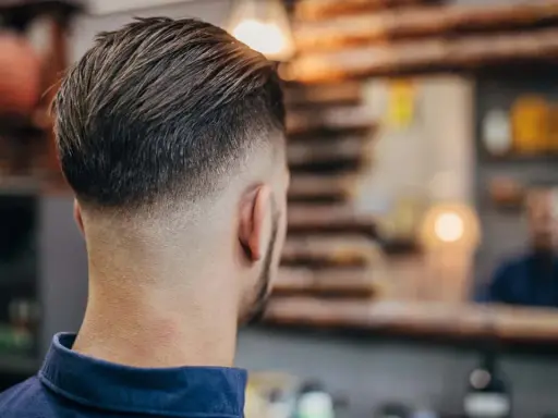 Mann mit einem modernen Haarschnitt, der einen **high taper** aufweist. Die Seiten sind kurz geschoren und gehen nahtlos in das längere Deckhaar über.