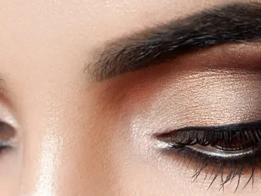 Nahaufnahme eines geschminkten Auges. Ein schimmernder Lidschatten wurde aufgetragen, mit einem dramatischen dunklen Smokey-Eye-Effekt.