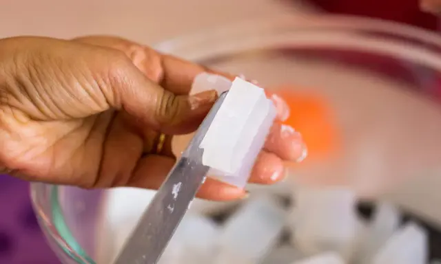 Hand schneidet klare Glycerinseife. Die Seife ist rein und wird bald auf der Haut angewendet.