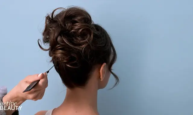 Eine Hand formt mit einem Kamm einen voluminösen, messy bun.