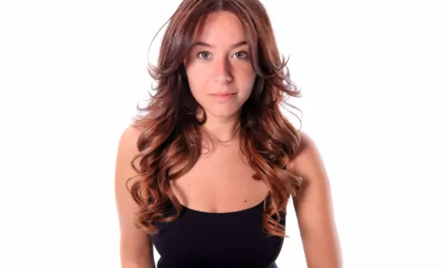 Frau mit langen, welligen Haaren, die einen Butterfly Cut trägt.