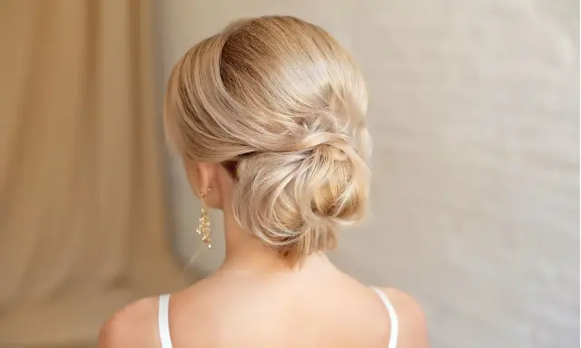 Elegante chignon frisur mit blondem Haar, kunstvoll zu einem tiefen Knoten gedreht.