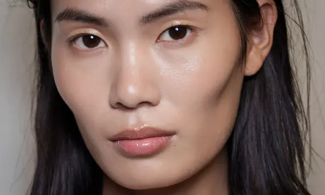 Ein Gesicht mit makellosem Teint und glänzenden Lippen. Das Make-up ist dezent, aber wirkungsvoll.