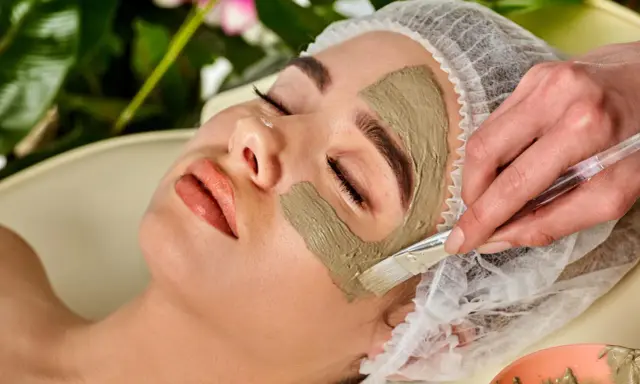 Eine Frau erhält eine Gesichtsmaske. Die heilerde-wirkung haut wird durch das Auftragen der Maske mit einem Pinsel gezeigt.